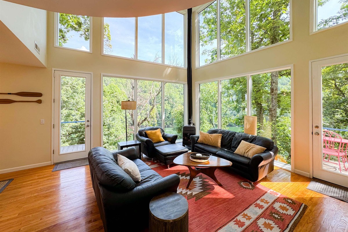 Spacious living room with a stunning mostly glass exterior wall. Unwind from a day of outdoor adventure and exploring hanging out in the trees!