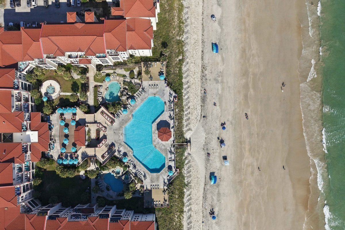Direct overhead aerial view showing the pool courtyard facilities, dune boardwalk, sand beach, and ocean shoreline.