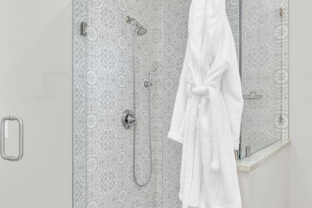 Walk-in shower with rainfall head and plush robe.