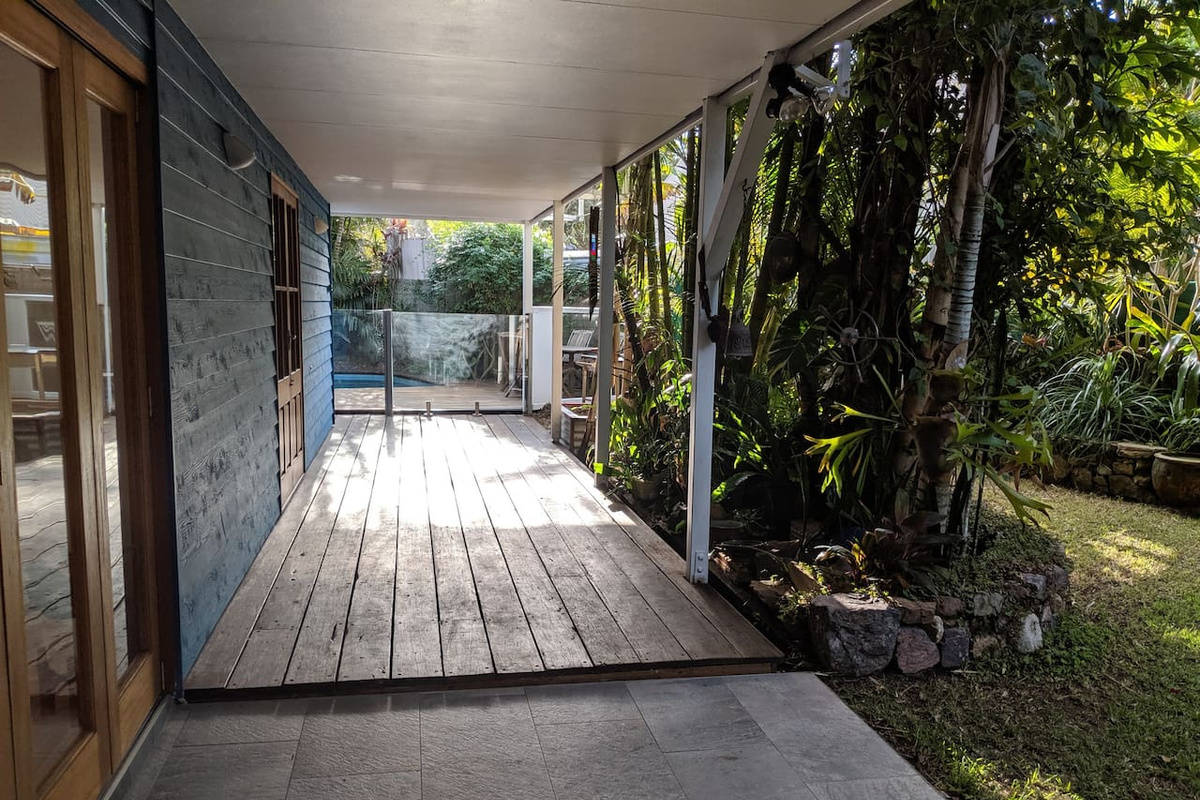 This sheltered timber walkway runs alongside Aaron's Beachside Boat House, connecting exterior access points with the garden and other parts of the property.