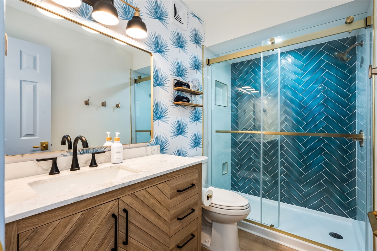 A modern bathroom featuring a walk-in shower with bold blue tile.
