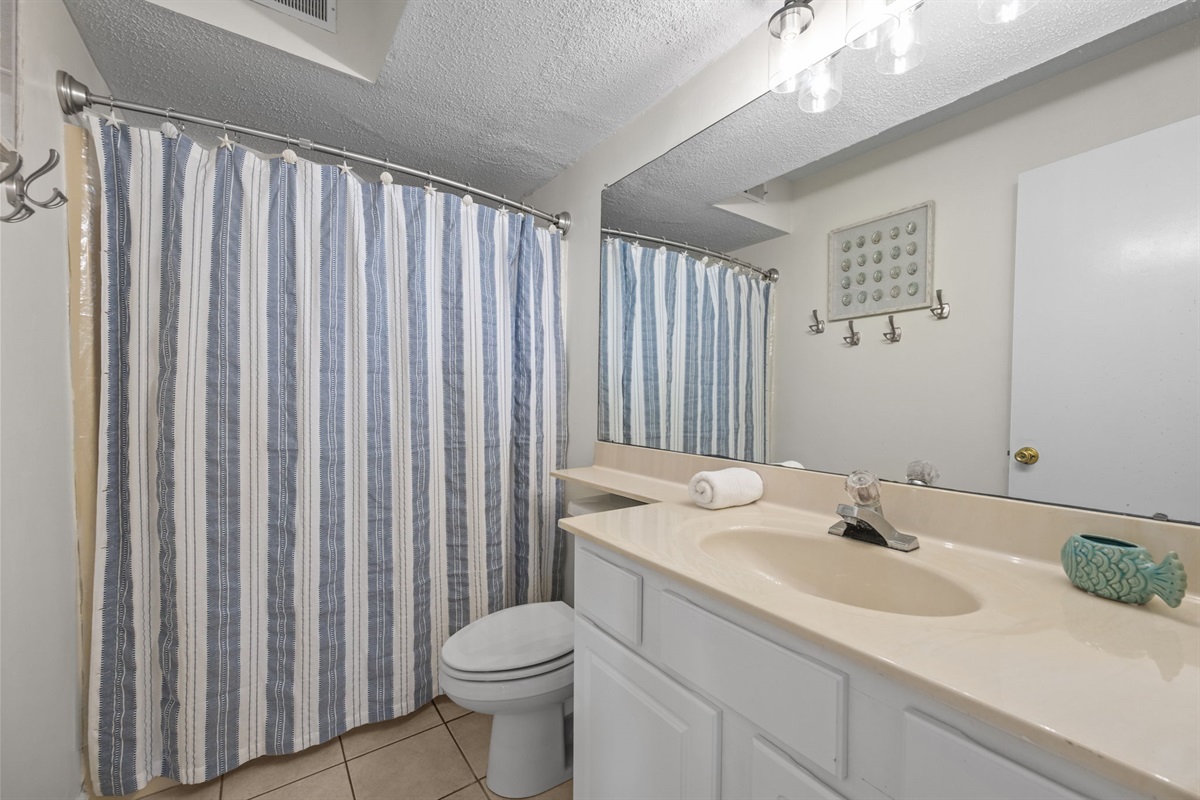 Full guest bathroom with shower/tub combo and coastal touches