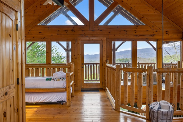 Upper level king suite — soaring A-frame skylights, wraparound Smoky Mountain views, private deck access, Smart TV, and a trundle that sleeps two more right in the room.
