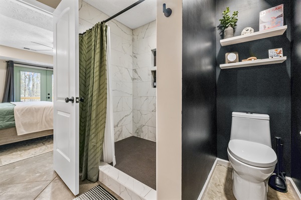 The first-floor master bathroom features a spacious walk-in shower with shampoo, conditioner, and body wash provided, plus a starter pack of toilet paper for your stay.