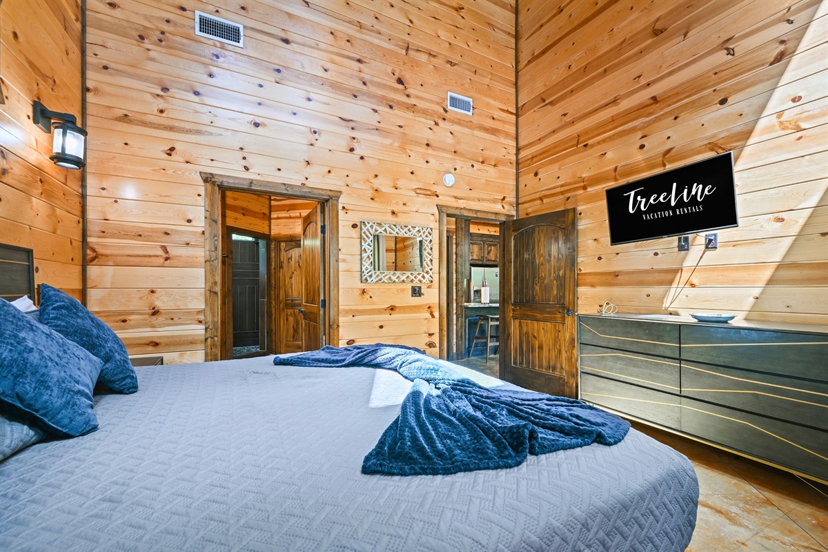 A spacious and serene bedroom with a king bed, dresser, and cabin-chic décor designed for restful nights.