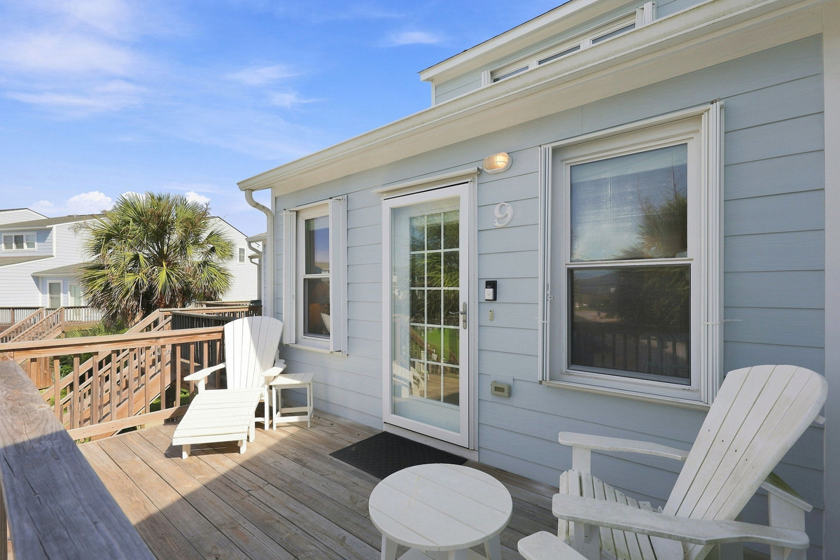 A cozy, light-blue exterior complete with classic Adirondack seating and a private entryway.