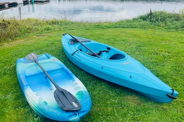 Two kayaks, one adult and one child size, rest at the lake’s edge, ready for paddling adventures. The calm water and shoreline create an inviting setting for family fun on the lake.