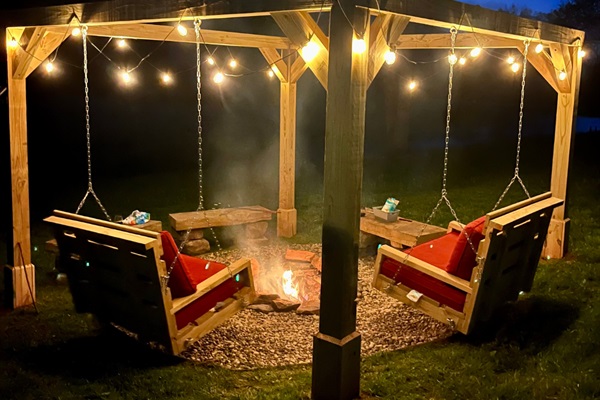 🔥✨ Fireside magic under the stars. Our custom swing fire pit is the coziest seat in the house—stories, s’mores, and starry skies included. 🌌🌲