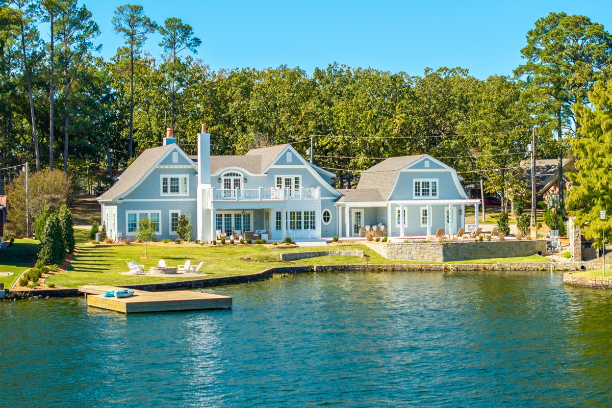 Back exterior with porch, pool, and landscaped lawn.