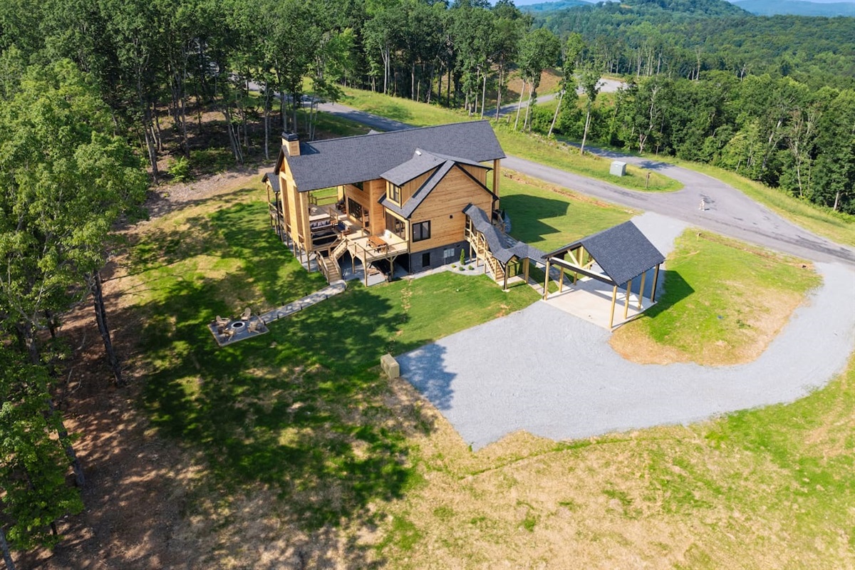 Experience the cabin’s full grandeur and serene location—this aerial shot captures the expansive property, mountain views, and winding road access.