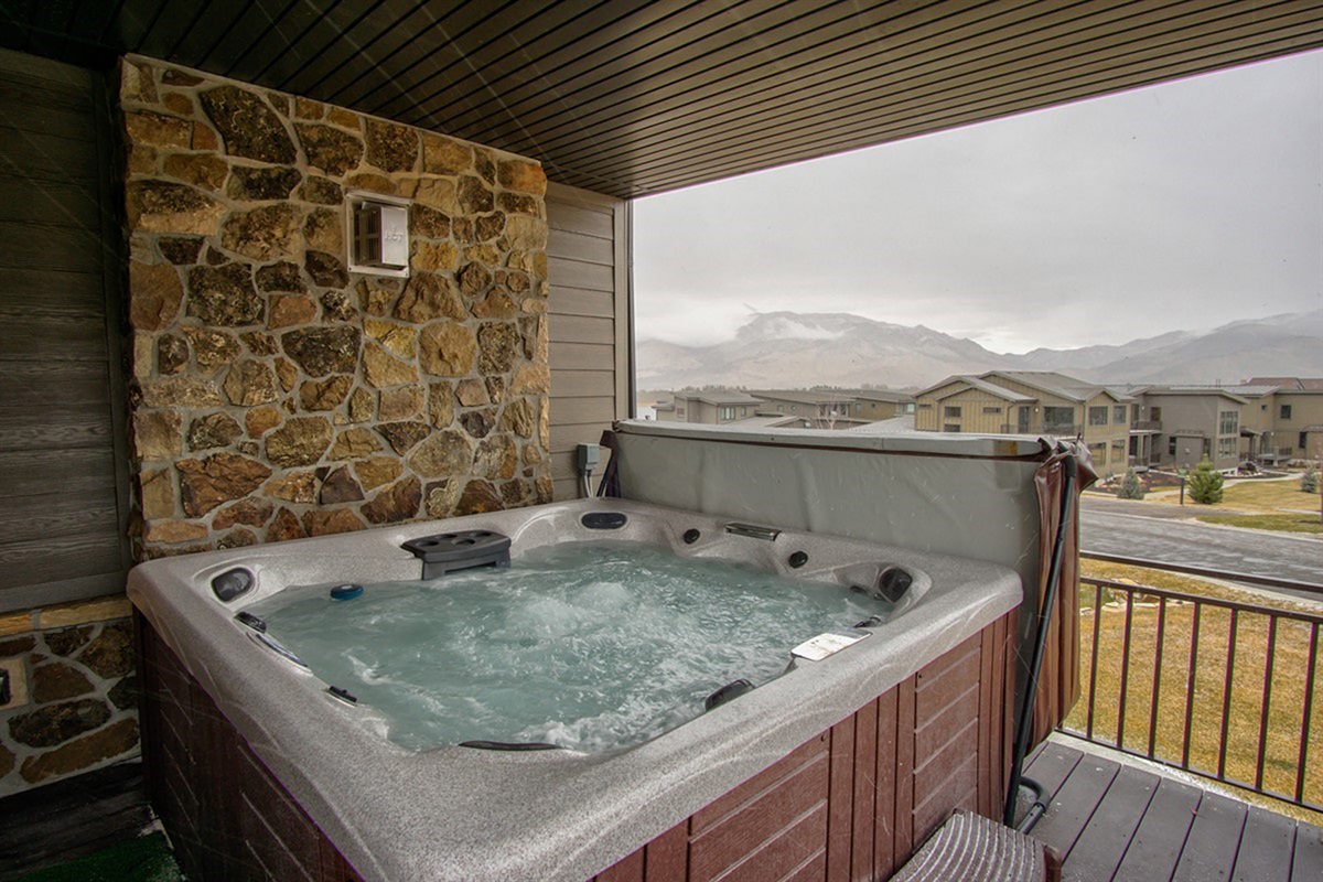 Unwind in your private hot tub retreat, tucked beneath a covered balcony and surrounded by rustic stonework—perfect for year-round indulgence.
