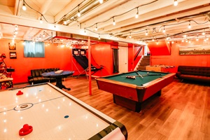 The bold red wall of this game room energizes the space, creating an electrifying backdrop for epic battles and laughter-filled evenings.