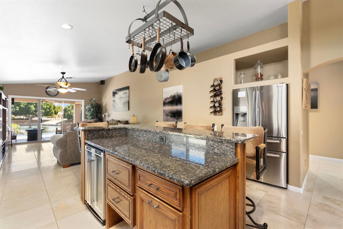 The expansive island with dual wine coolers and a hanging pot rack is the heart of the kitchen — perfect for entertaining while meals are being prepared.