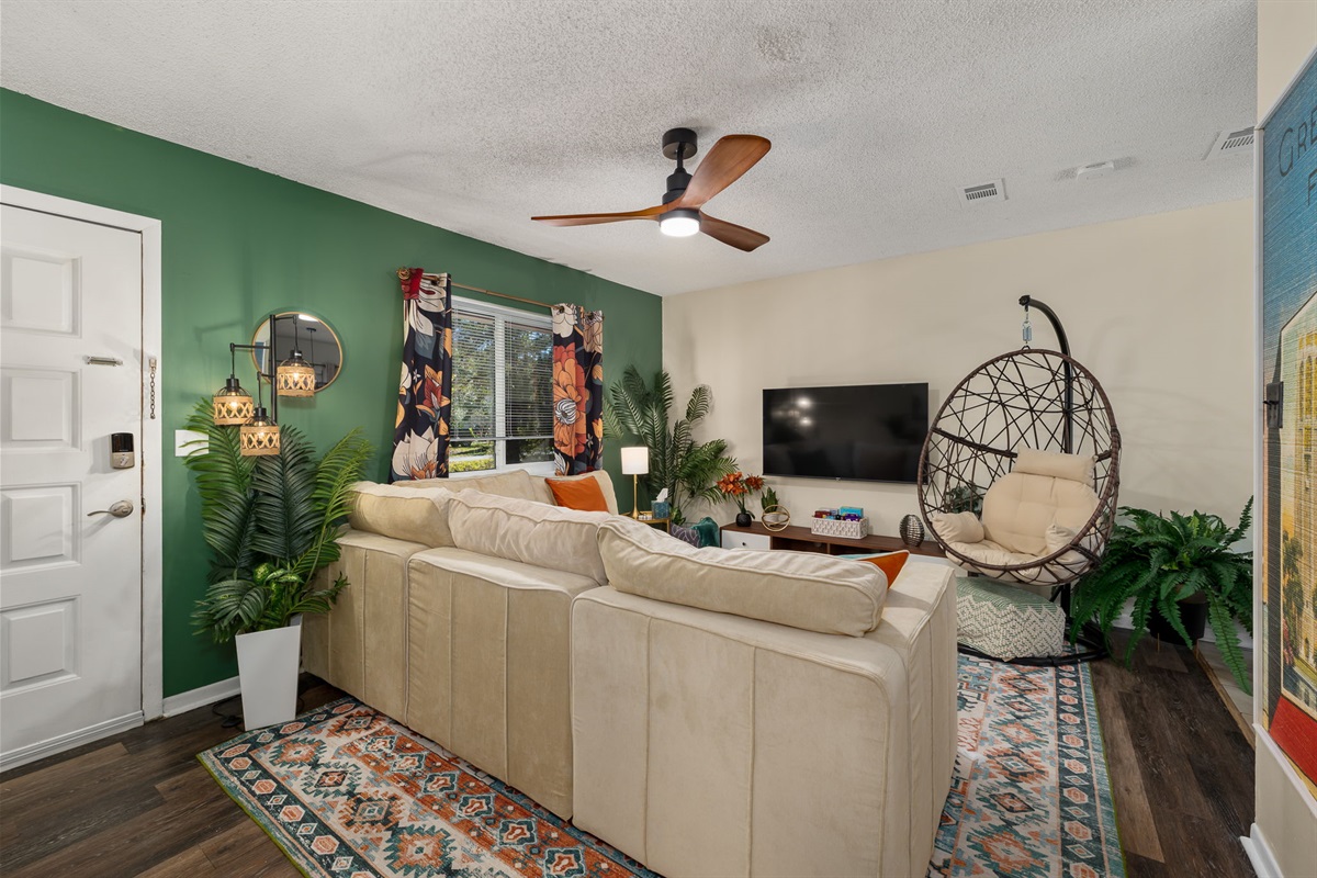 The cozy living room with a 55" smart TV, plush sectional couch, and cozy hammock chair.