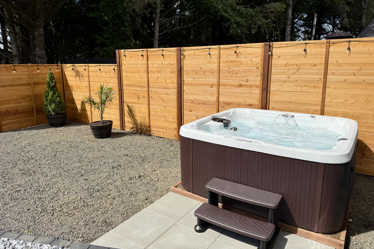 The Flamingo Fun Room side's hot tub, tucked into its own fully fenced gravel courtyard. Two houses, two tubs, no waiting for a turn.