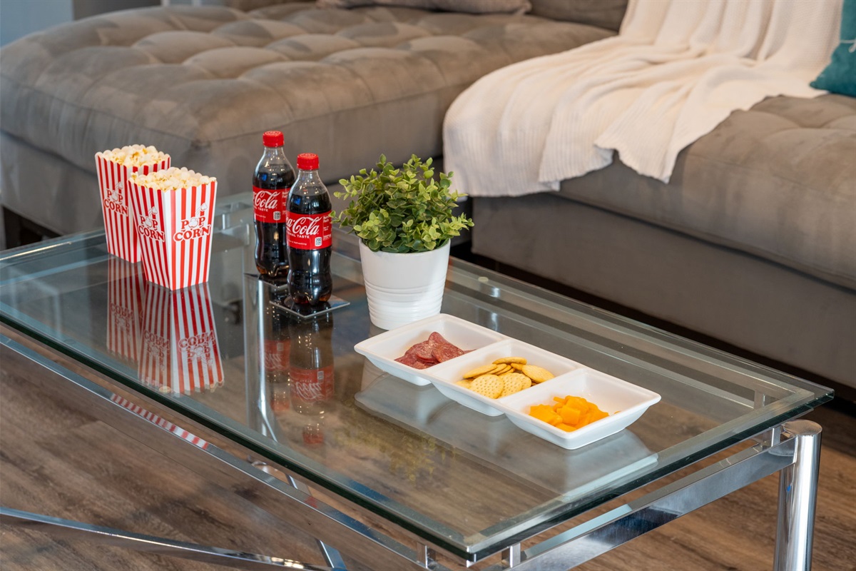 A blend of elegant chrome and glass furnishings with practical elements like the electric fireplace and organized layout.