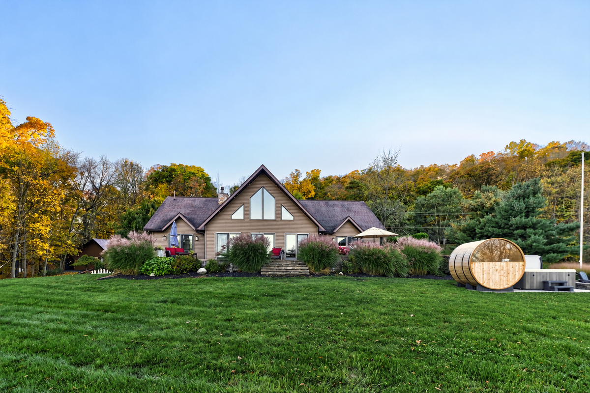 Rear exterior with expansive lawn and barrel sauna