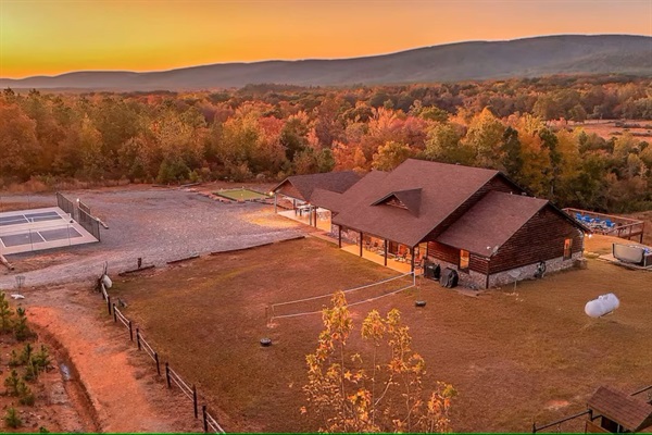 Golden hour aerial with mountains glowing behind the cabin.