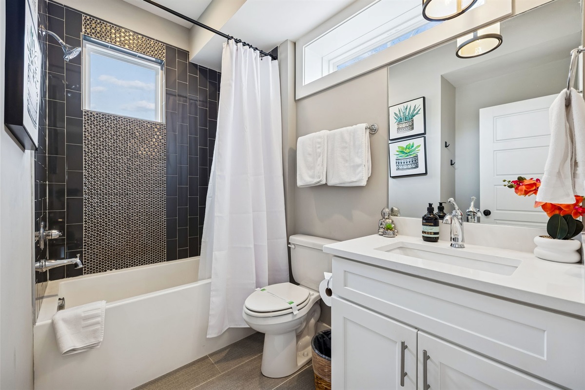 - Clean lines and bold navy tile give this bathroom a modern, refreshing feel - Round mirror, open shelving, and thoughtful touches make it both stylish and functional - Perfect for freshening up after a day out or unwinding with a relaxing soak