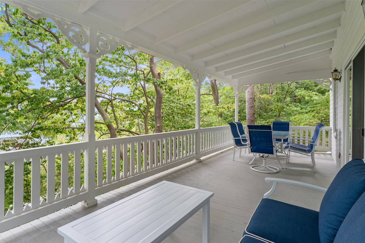 Charming covered porch surrounded by trees, perfect for relaxing with morning coffee or outdoor dining.