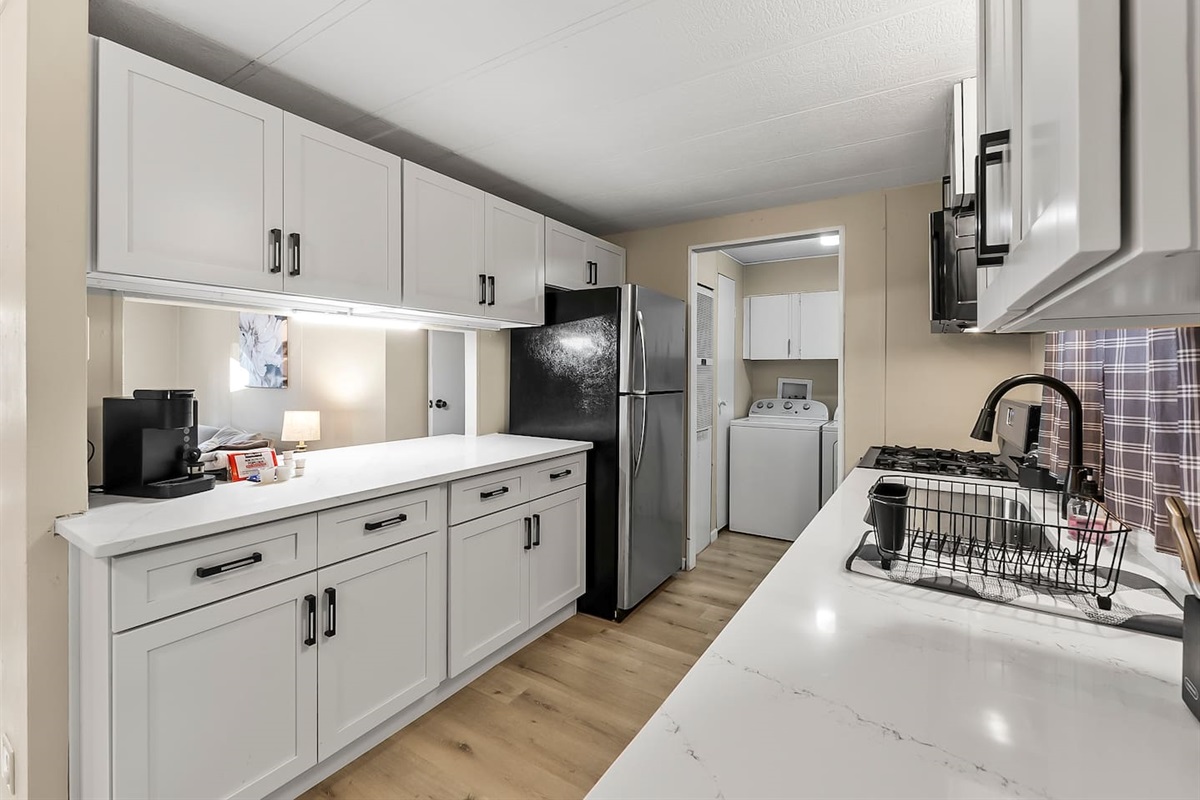 Modern kitchen with sleek white cabinetry and full-size stainless steel appliances for all your cooking needs.