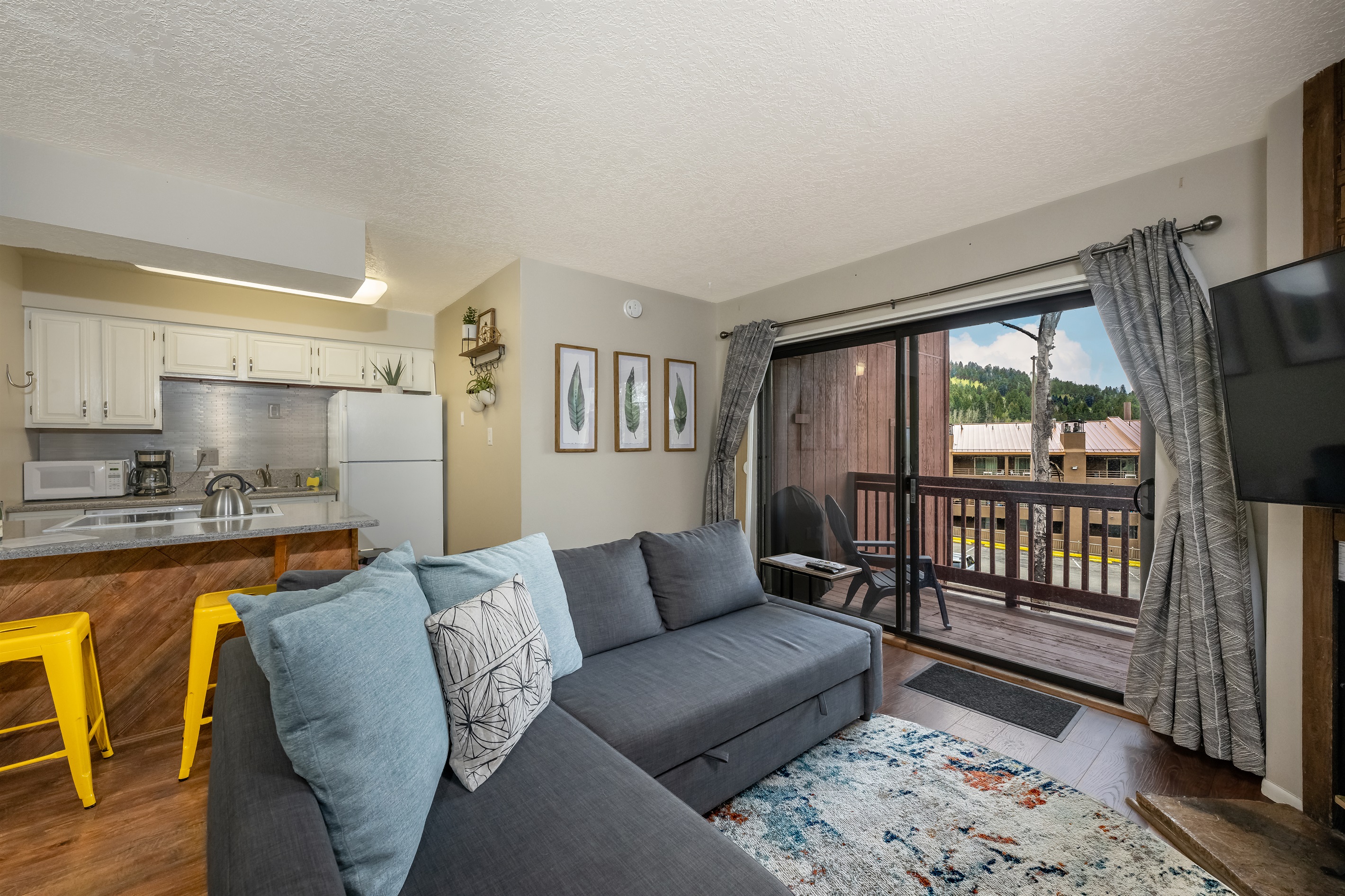 Living room, kitchen, and balcony with mountain views.