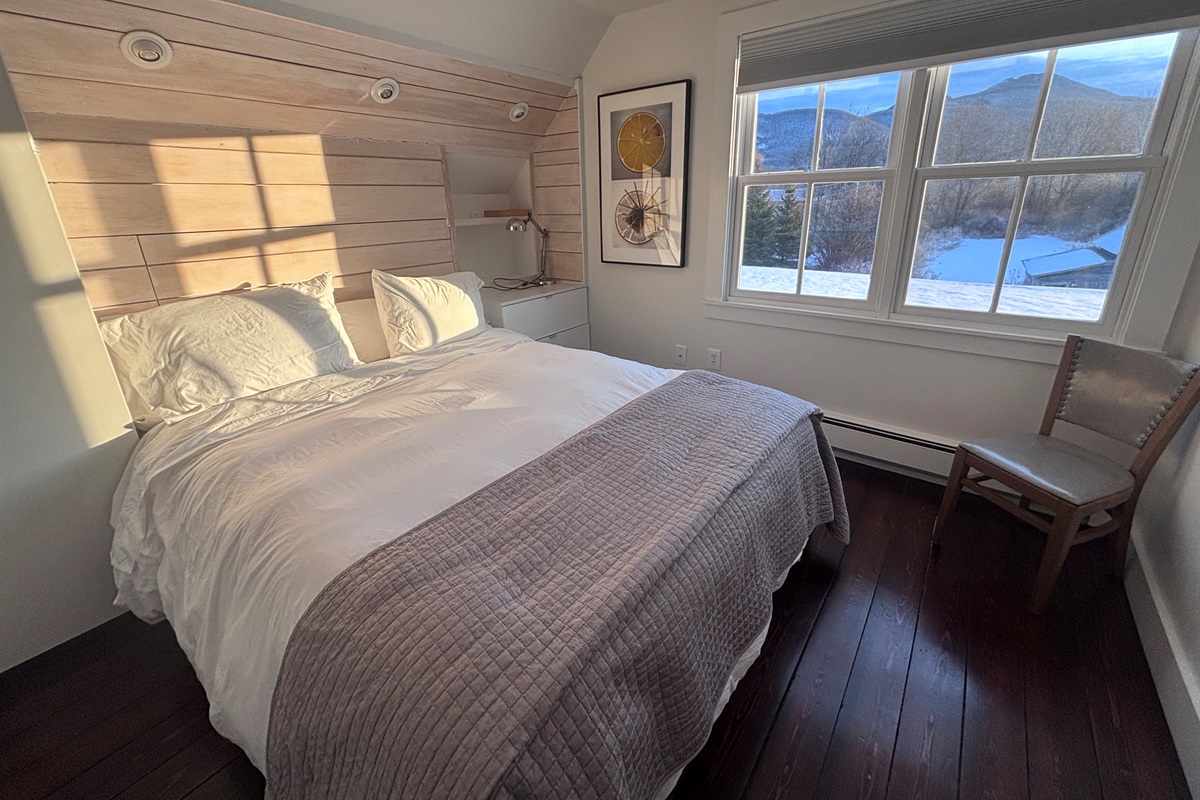 Cozy bedroom retreat with plush bedding, wood accents, and peaceful morning light.