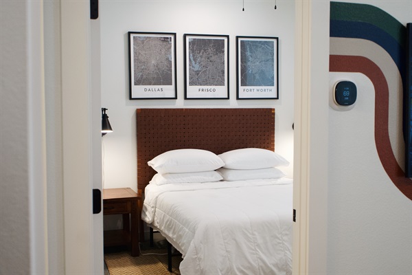 Comfortable bedroom with quality linens and framed local maps, creating a calm and restful space.