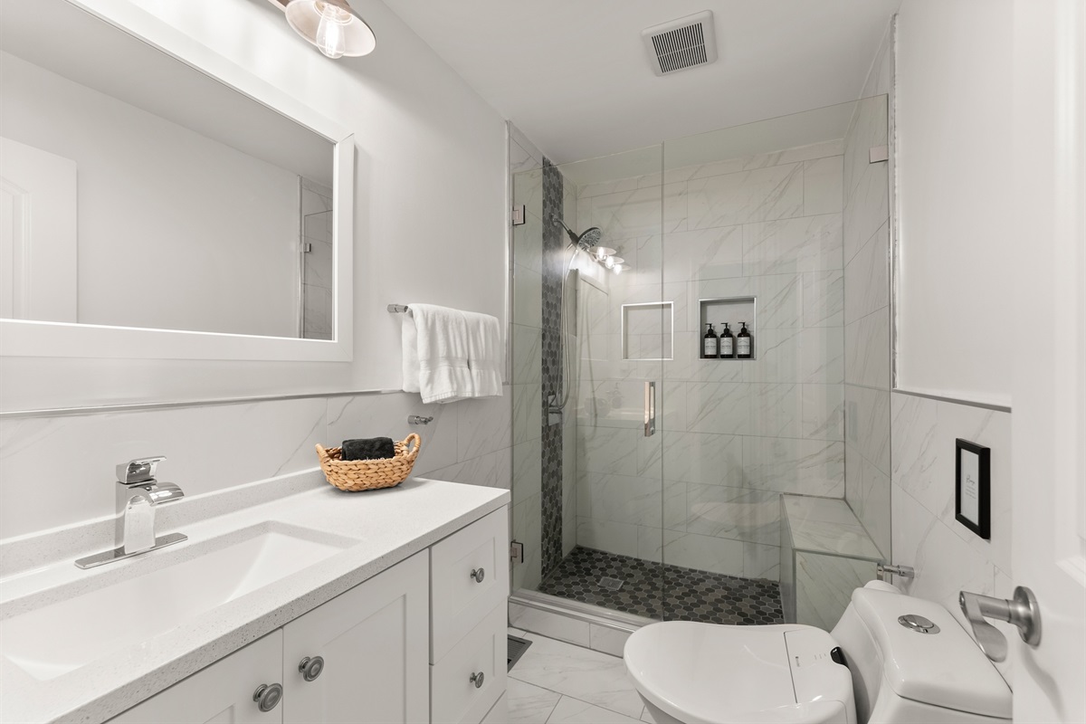 Master bathroom with bidet and tiled shower with bench.