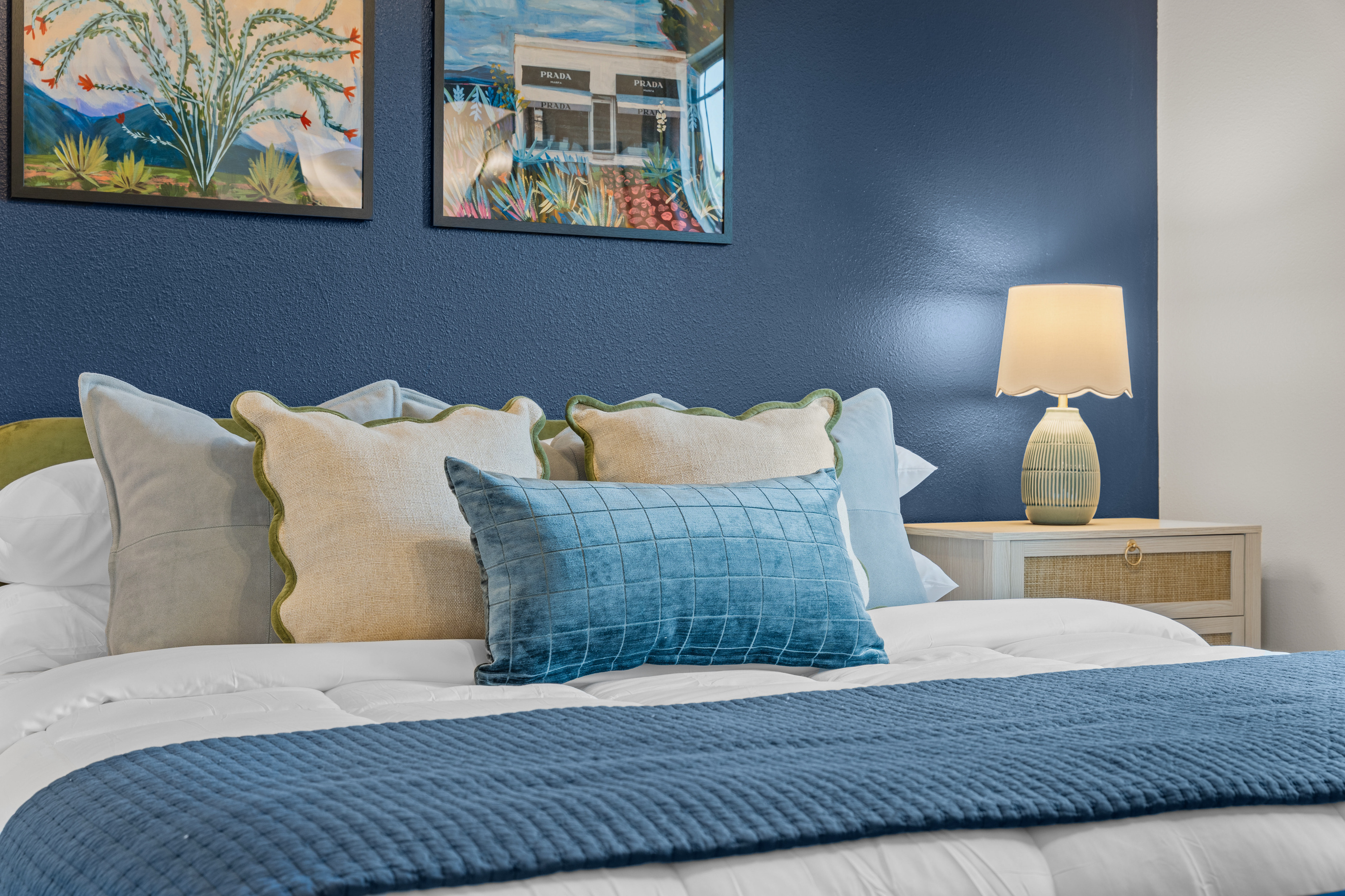 Scalloped pillows and a green glass lamp warm up the navy Marfa king bed.