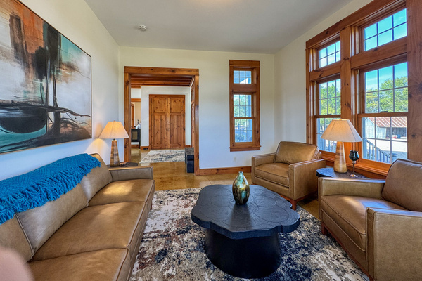 Front sitting room with leather seating and large windows.