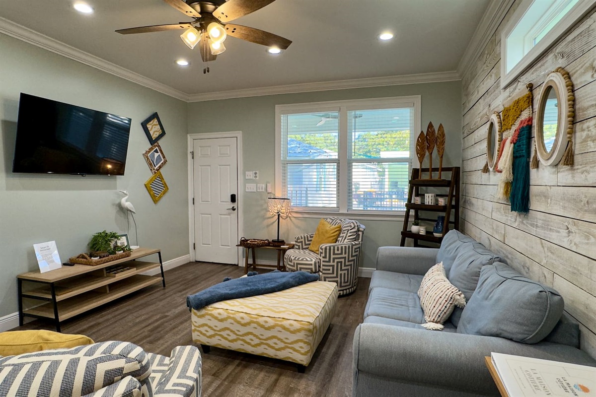 Welcoming living area with cozy seating, coastal accents, and a wall-mounted TV for relaxing evenings.