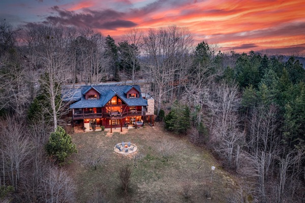 The back of the beautiful "Blessed Sunset" mountain retreat home overlooking the back yard! Stunning A-frame, wrap-around porch, screened-in patio, outdoor fireplace, outdoor dining table, sauna, hot tub, outdoor couch, and more!