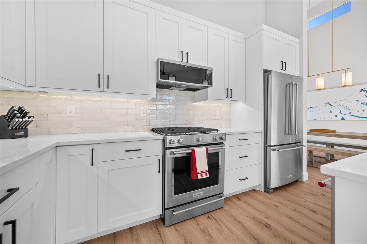 Stainless steel gas range and microwave with spacious cabinetry and subway tile backsplash.