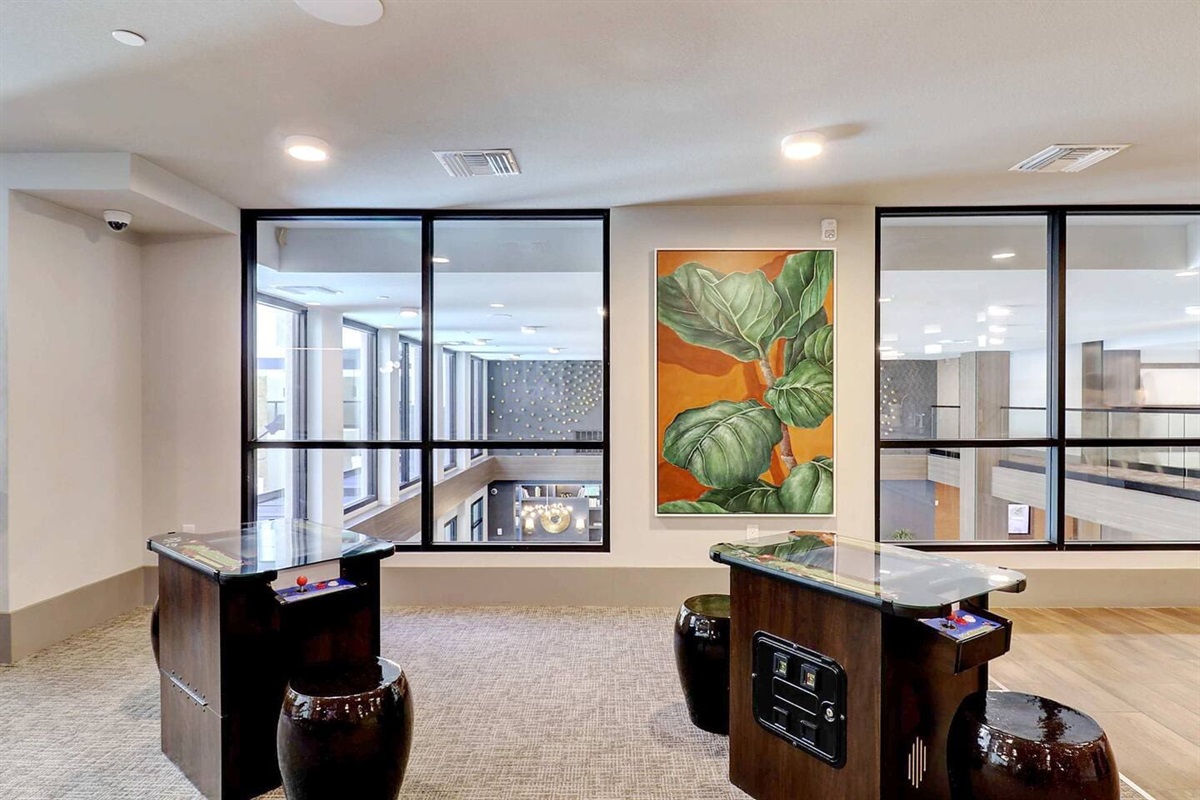 - Take a break in the game room featuring retro arcade tables and cozy seating   - Natural lighting and bold artwork create a playful, modern lounge atmosphere   - Perfect for friendly competitions or relaxing between activities indoors