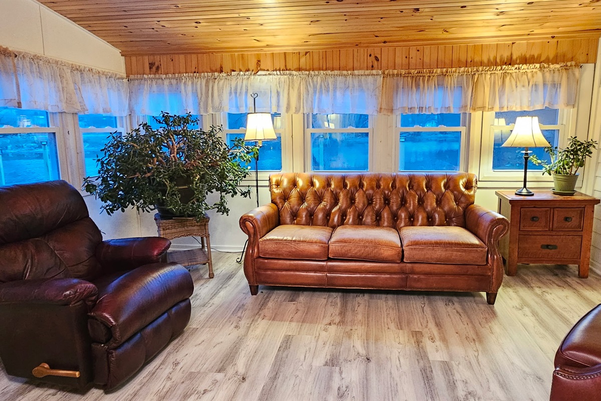Sunroom overlooking the water with stylish leather seating.