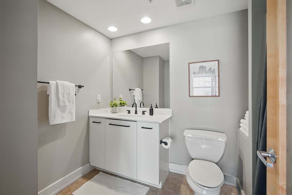 Bright, clean bathroom with a large mirror, soft lighting, and modern fixtures. Includes plush towels, essential toiletries, and thoughtful design for a relaxing start and end to your day.