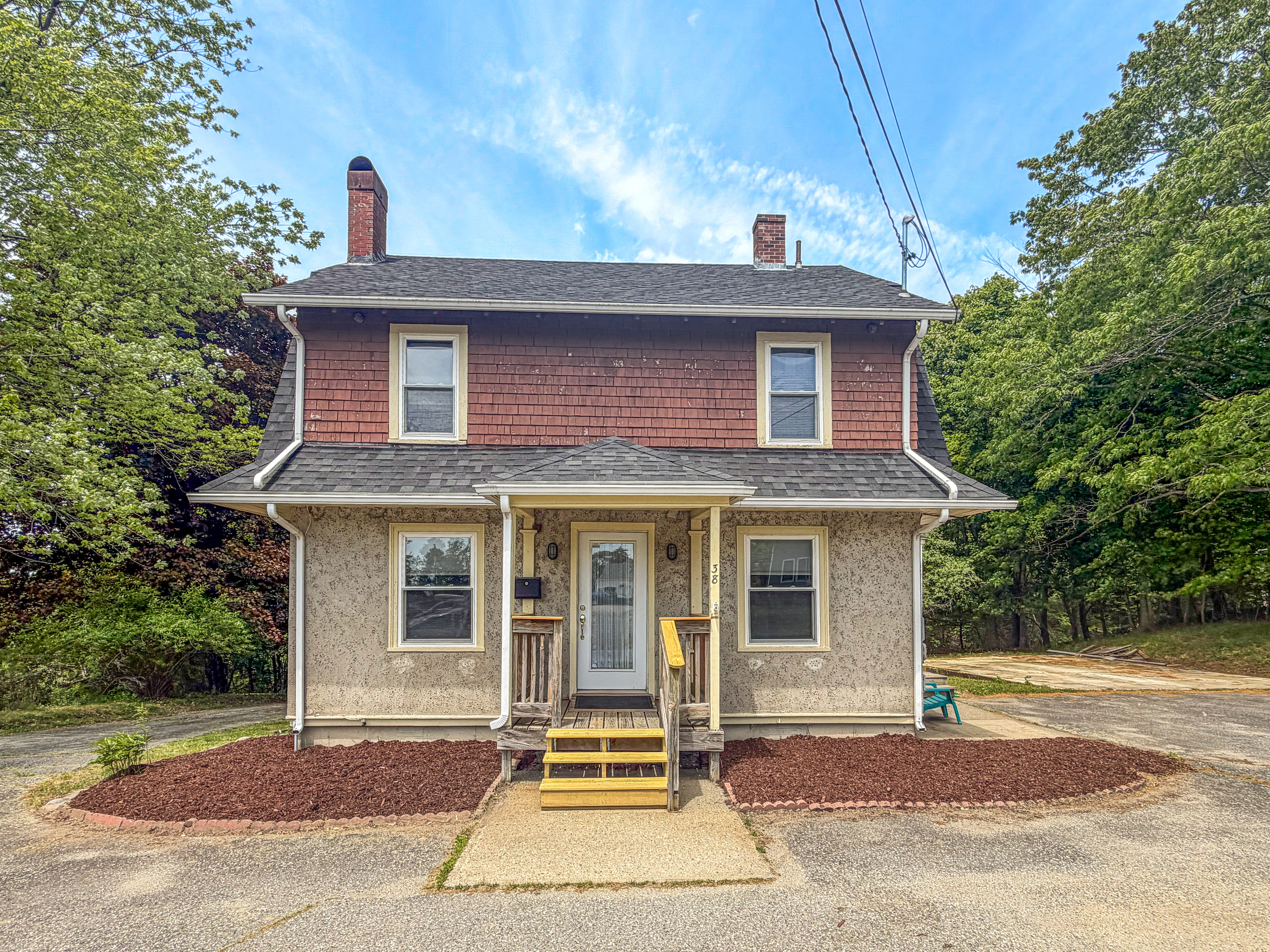 Historic stone-pressed stucco siding defines the exterior of this private two-story Downeast vacation home. This architectural asset establishes the property identity, while the surrounding paved parking area provides effortless regional transit access.