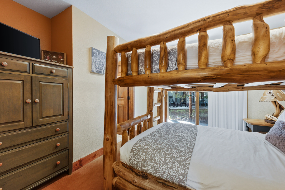 Lower level guest bedroom #3 with Queen-over-Queen bunk, sliding door for patio access, tv and attached bathroom with shower. 