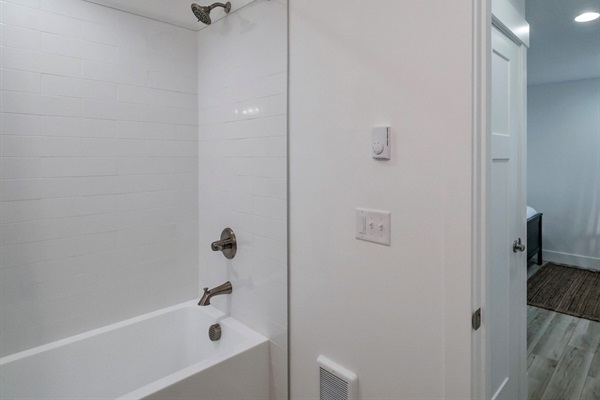 The lower-level guest suite features its own private bathroom with a white-tile bathtub—perfect for a relaxing soak!