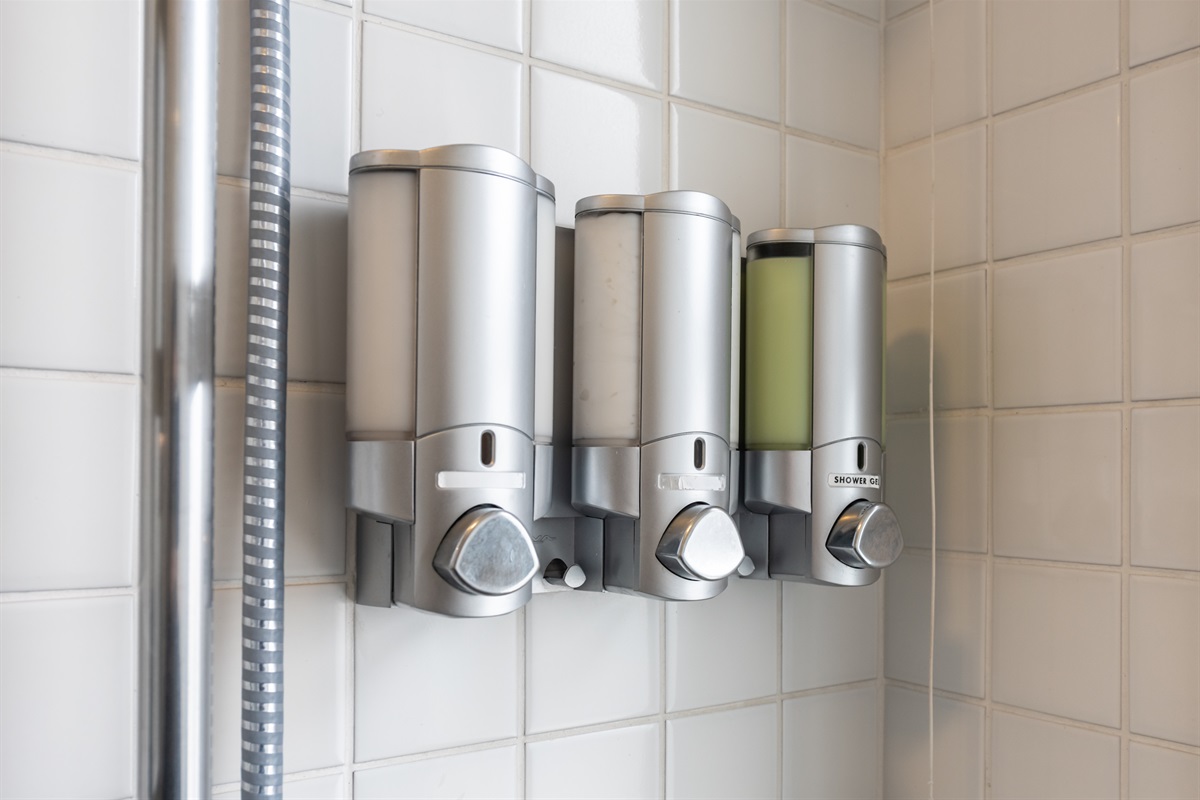 Dispensers com shampoo, condicionador e sabonete líquido disponíveis para os hóspedes.