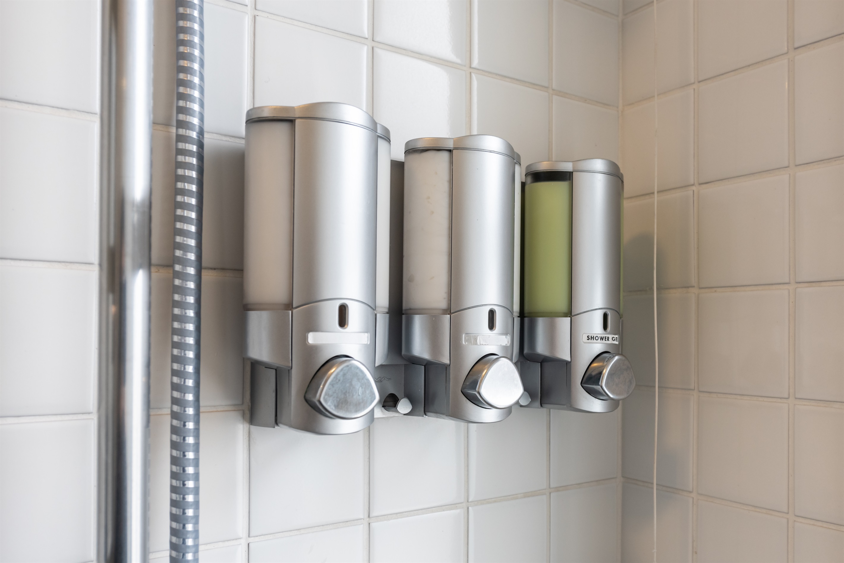 Dispensers com shampoo, condicionador e sabonete líquido disponíveis para os hóspedes.
