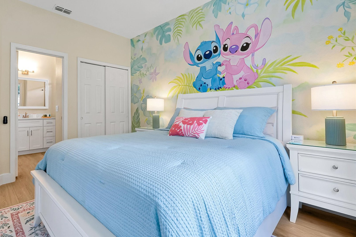 Stitch Queen Retreat: Main-floor queen bedroom with a hand-painted Stitch and Angel tropical mural, TV and abundant natural light.
