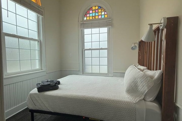 Bright and stylish front bedroom offering a queen bed, premium bedding, gentle lighting, and convenient essentials to make you feel at home.