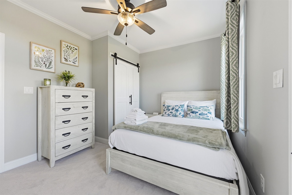 Main master bedroom with soft coastal d&eacute;cor, Smart TV, and private bathroom access