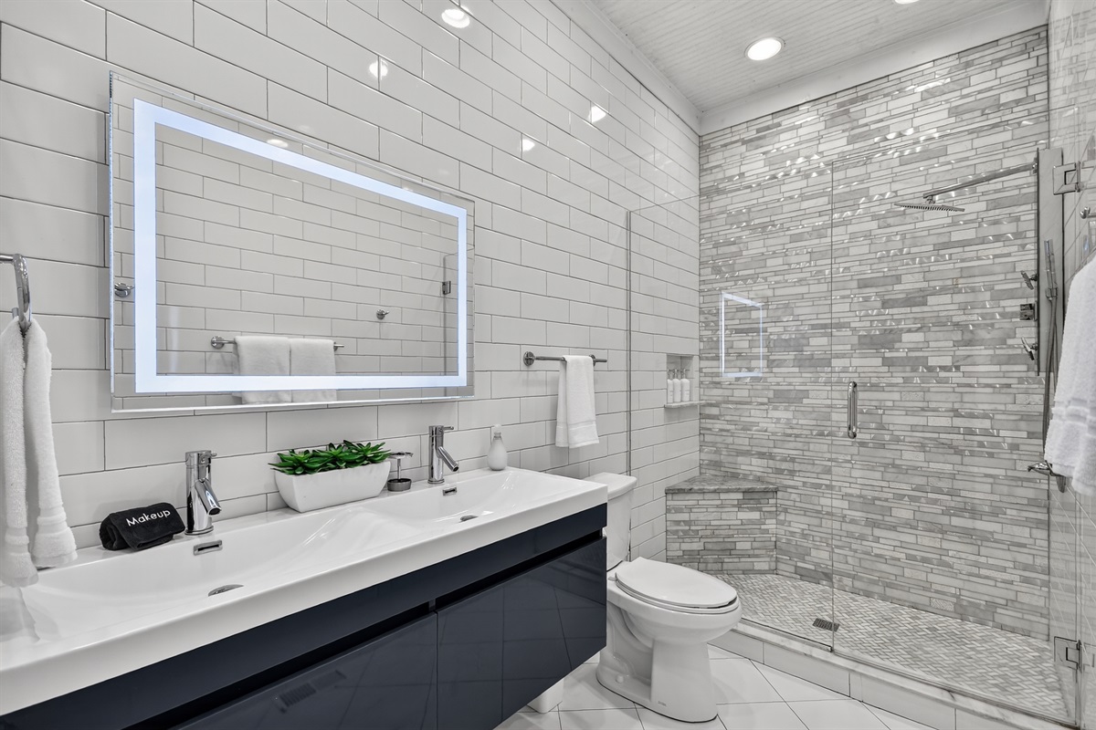 Modern and luxurious, this spa-style bathroom features a double vanity, LED mirror, and rainfall shower&mdash;everything you need to refresh after a day out in Blue Ridge.