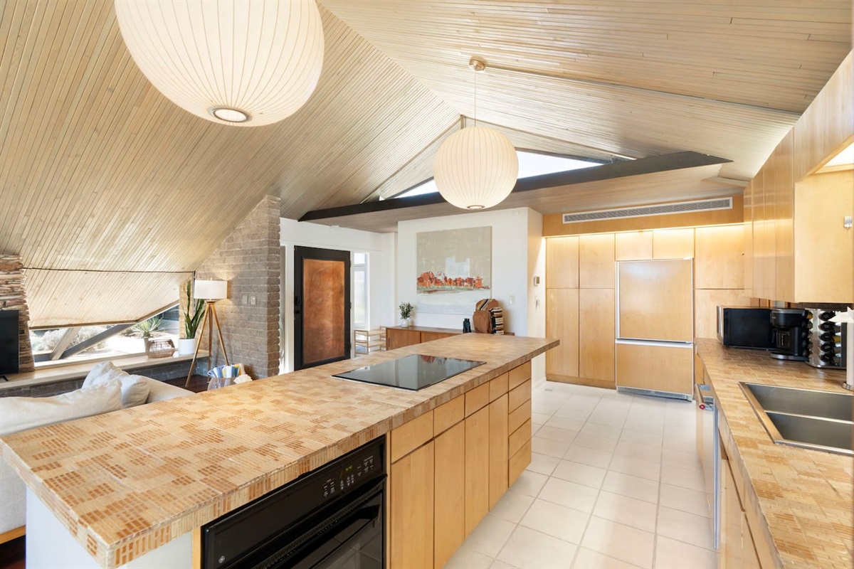 Spacious open-concept kitchen with vaulted wood ceilings, large island cooktop, and seamless flow into the living area.