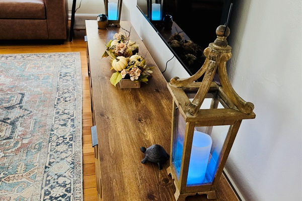 A 65\" mounted TV anchors the living room, while lanterns and flameless candles add a soft, ambient glow for cozy evenings