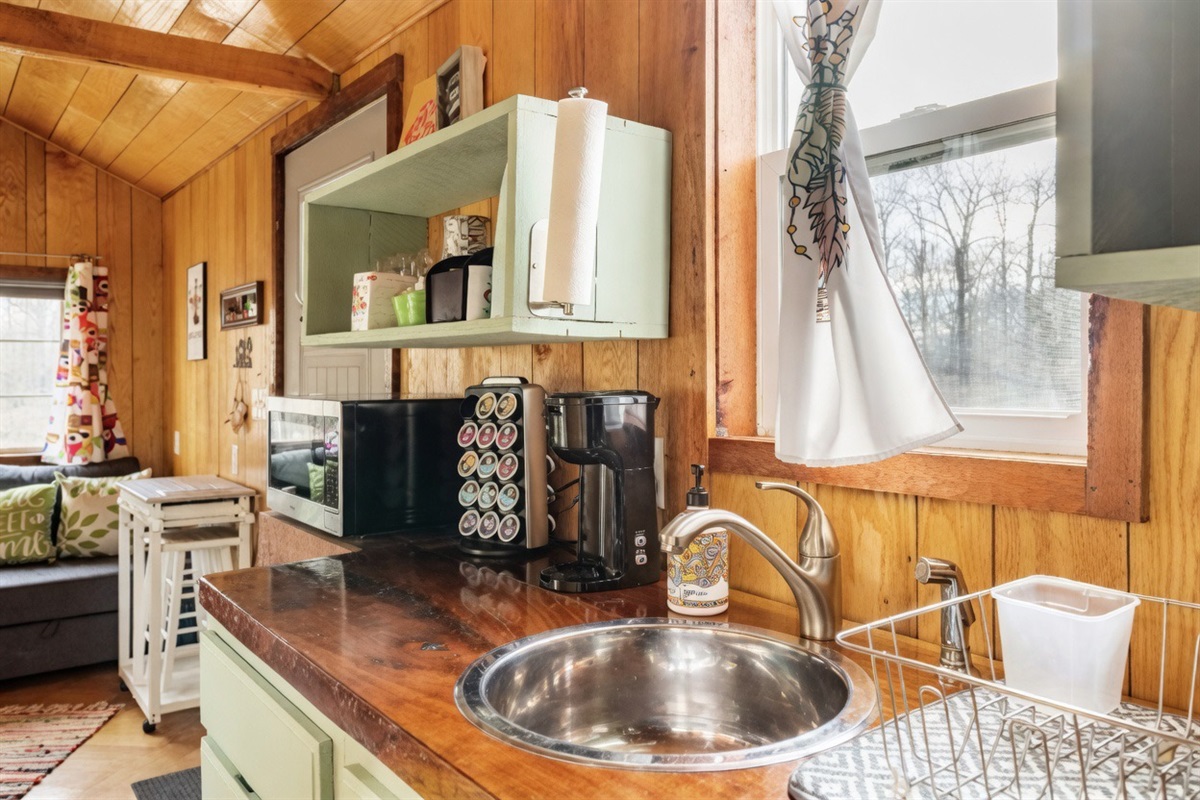 Embrace the charm of a well-equipped kitchenette that includes a double electric hot plate, toaster, microwave, air fryer, electric skillet, spice rack and coffee bar.