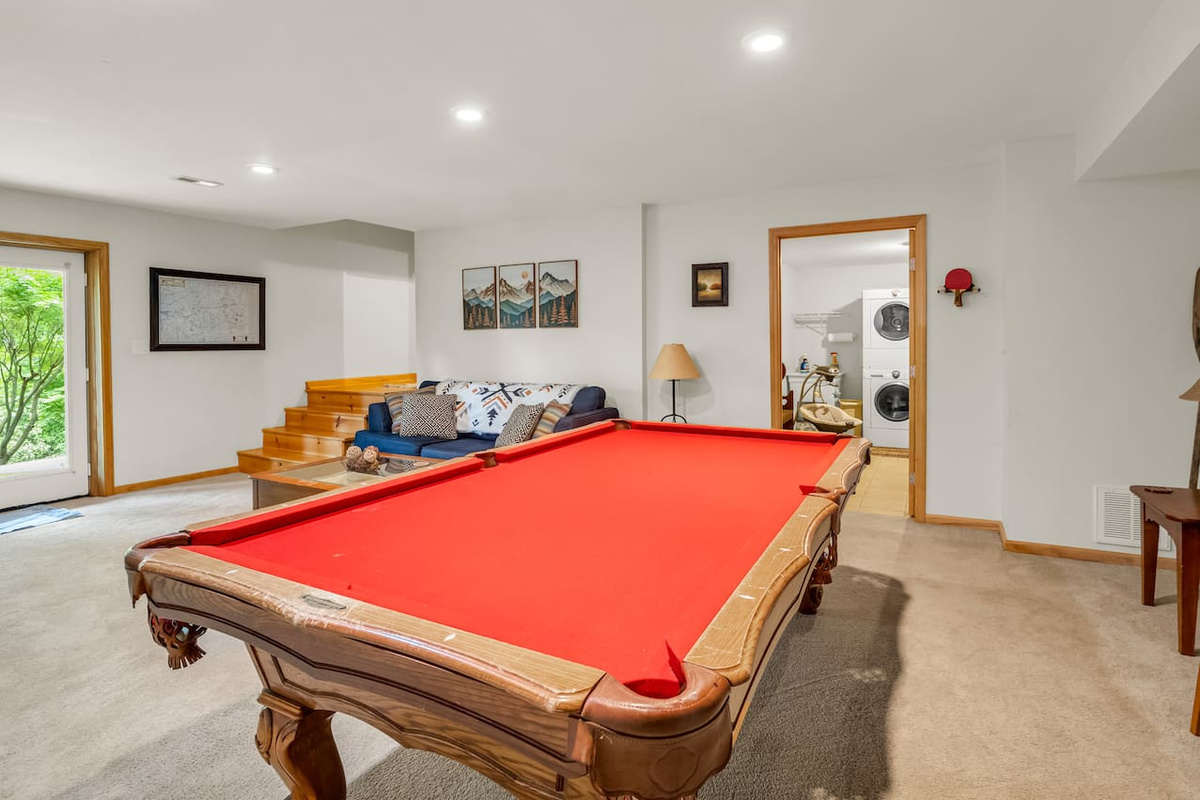Basement with pool table, comfortable seating, plenty of board games, television, dart board, and exterior view of laundry area